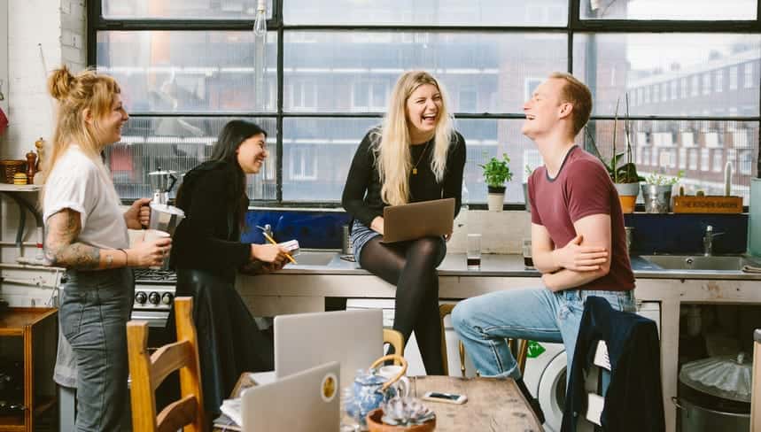 Four people laughing in front of a computer