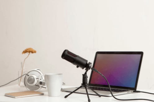 podcast recording tools including laptop, microphone, and headphones