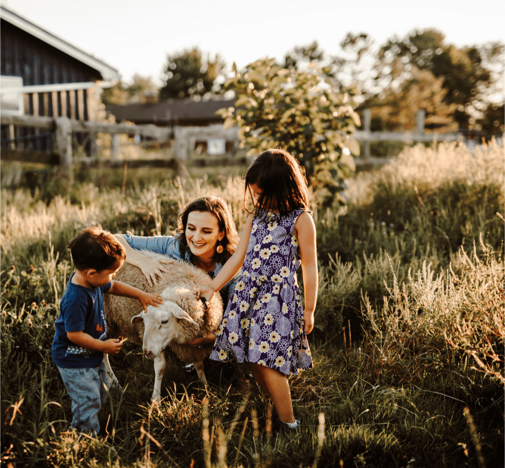 Photo of Nathalie with her kids and a sheep